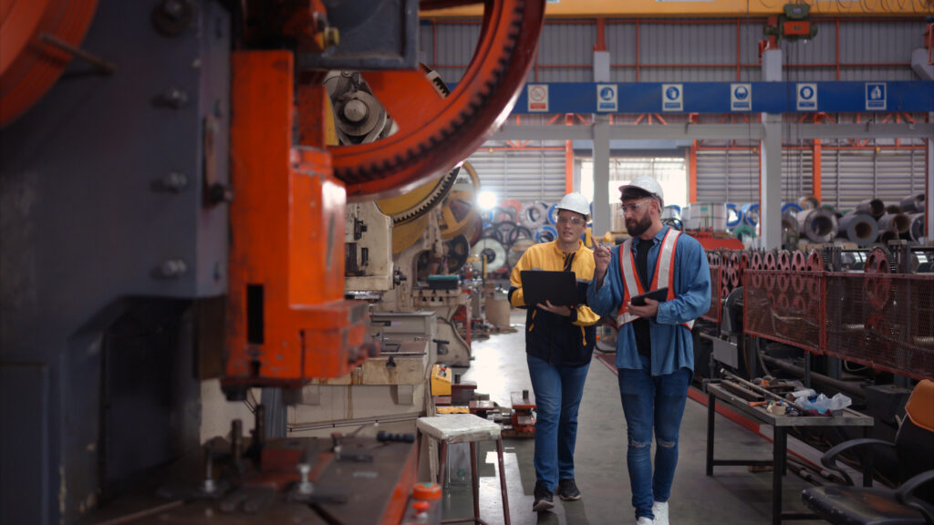 Engineer and technician discussing machinery in factory to plan