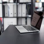 MacBook Pro displayed on a minimalist office desk with shelves in the background.