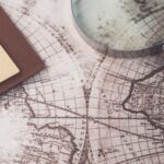 A close-up of a vintage map, magnifying glass, and notebook, perfect for research themes.