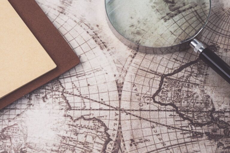 A close-up of a vintage map, magnifying glass, and notebook, perfect for research themes.